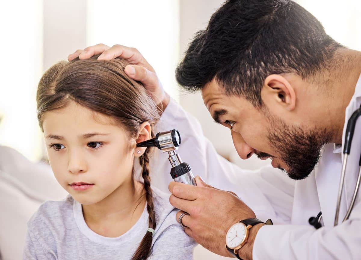 Doctor looking into child's ear using a medical device and determining if ear tubes are the right procedure